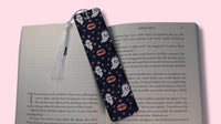 Bookmark with ghost and vampire lips design on an open book against a pink background