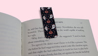 Book with a decorative bookmark featuring ghosts and vampire lips on a pink background