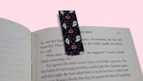 Book with a decorative bookmark featuring ghosts and vampire lips on a pink background