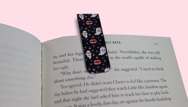 Book with a decorative bookmark featuring ghosts and vampire lips on a pink background