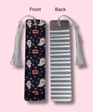 Front and Back side of a bookmark, one side showing a ghost and vampire lips design and the other side showing the aluminum look, on a pink background.