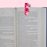 Open book with a pink hearts bookmark on a pink background