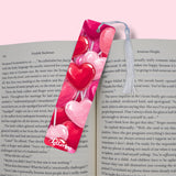 Heart-shaped pink and red bookmark on an open book with visible text.