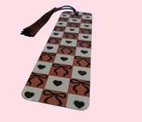 Aluminum bookmark with checkered pattern, bows, and hearts on a pink background