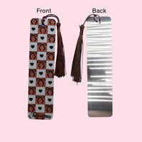 Bookmark with tassels on a pink background, showing front and back designs.