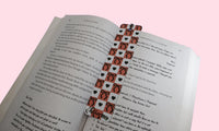 Open book with a decorative checkerboard design bookmark on a pink background