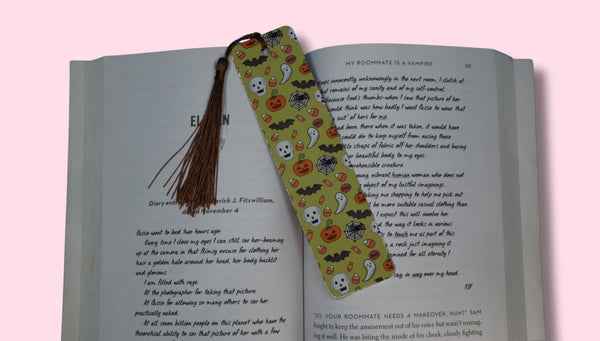 Open book with a colorful bookmark featuring Halloween designs on a pink background