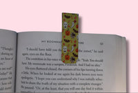 Colorful bookmark with Halloween designs on an open book against a pink background