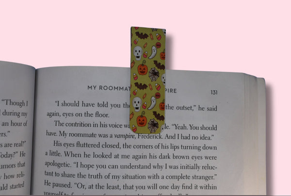 Colorful bookmark with Halloween designs on an open book against a pink background
