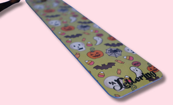 Halloween-themed bookmark with cartoon designs on a pink background