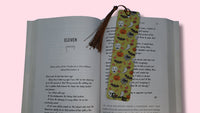 Open book with a decorative bookmark featuring Halloween-themed illustrations on a pink background