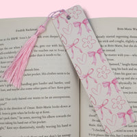 Pink aluminum bookmark featuring bows and hearts on an open book with a pink background