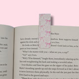 Open book with a pink bookmark featuring hearts and bows on a pink background