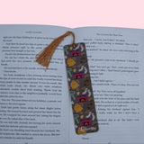 Decorative bookmark with tassel on an open book against a pink background