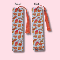 Fall leaves-patterned bookmark with orange tassels on a pink background
