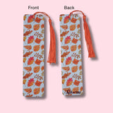Fall leaves-patterned bookmark with orange tassels on a pink background