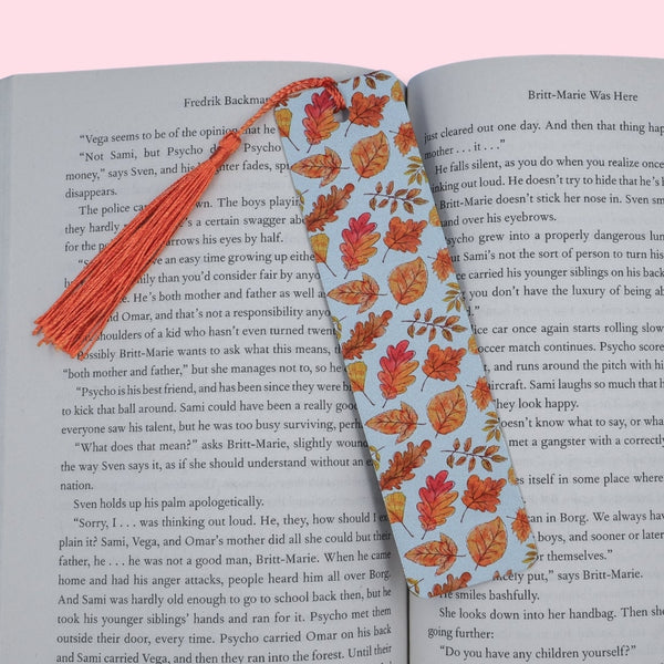 Open book with a leaves bookmark on a pink background