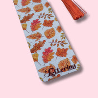 Decorative bookmark with autumn leaf pattern on a pink background