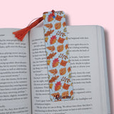 Book with a colorful leaf-patterned bookmark on a pink background