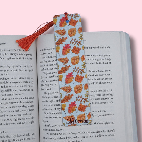 Book with a colorful leaf-patterned bookmark on a pink background