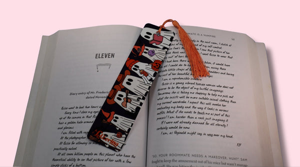 Book with a spooky decorative bookmark on a pink background