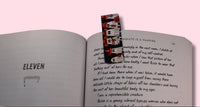Open book with a colorful ghost bookmark on a pink background