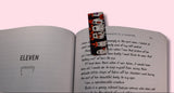Open book with a colorful ghost bookmark on a pink background