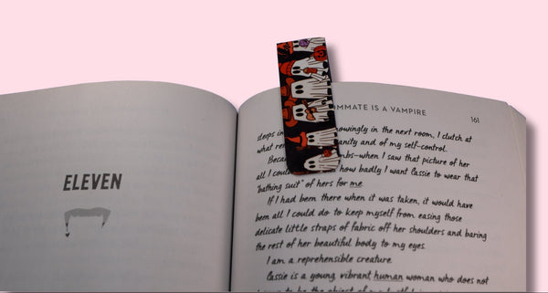 Open book with a colorful ghost bookmark on a pink background