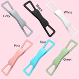Six silicone strap-like accessories shown in different colors on a light pink background, labeled Gray, Black, White, Pink, Teal, and Green.