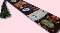 Halloween-themed bookmark with cartoonish mummy, pumpkin, and vampire design on a pink background.