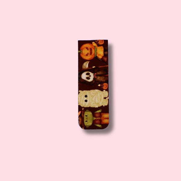 Decorative magnetic bookmark with cartoon character dressed in festive Haloween costumes on a pink background