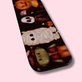 Magnetic bookmark with Halloween-themed design featuring cartoon characters dressed in pumpkins and ghosts costumes on a pink background