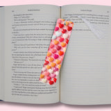 Open book with a decorative heart-shaped bookmark on a pink background