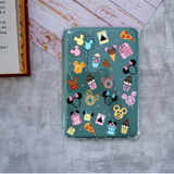 A clear-edged tablet case with a teal background printed with colorful cartoon dessert, including cupcakes, ice cream cones, and pizza slices, shown on a textured gray surface.