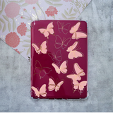 Clear Kindle Case with pink butterfly decals and outlines of butterflies on a magenta kindle.