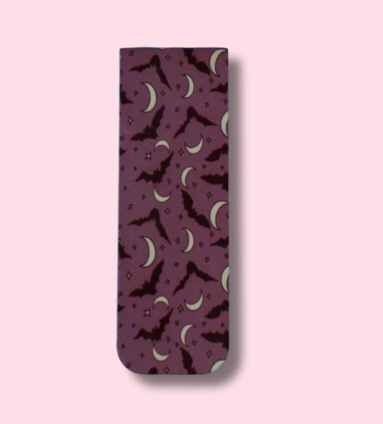 a bookmark with bats and crescent moons patterns on a pink background