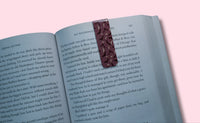 Open book with a decorative bookmark featuring bats and crescent moons on a pink background