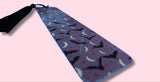 Purple bookmark with bat and moon pattern on a pink background