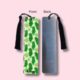 Bookmark with green pickles design on one side and plain backside on the other, on a pink background.