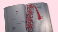 Open book with a pink bookmark featuring ghosts illustrations on a pink background