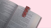 Open book with a colorful bookmark on a pink background