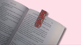 Open book with a colorful bookmark on a pink background