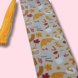 Decorative aluminum bookmark with autumn-themed pattern on a light pink background