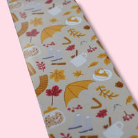 Aluminum bookmark with autumn-themed pattern and yellow tassel on a pink background