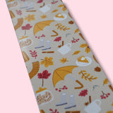 Aluminum bookmark with autumn-themed pattern and yellow tassel on a pink background