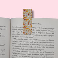 Autumn-patterned magnetic bookmark on an open book with a pink background