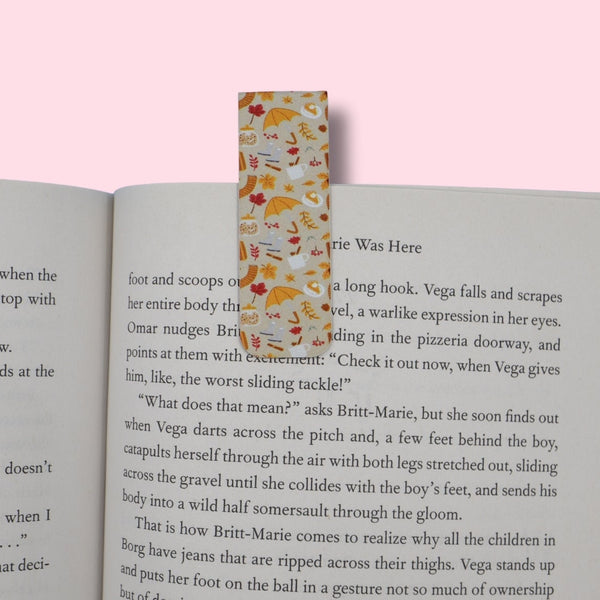 Autumn-patterned magnetic bookmark on an open book with a pink background