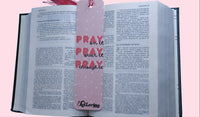 Open book with a pink bookmark featuring quote Pray on it, Pray over it, Pray through it on a pink background