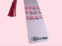 Decorative bookmark with quote "Pray on it, Pray over it, Pray through it" and salmon-color tassel on a pink background