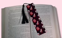 Bookmark with skull and crossbones design on an open book against a pink background